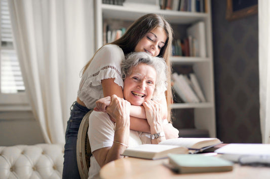 Grnadma smiling with teeth shining, and daughter by her side hugging